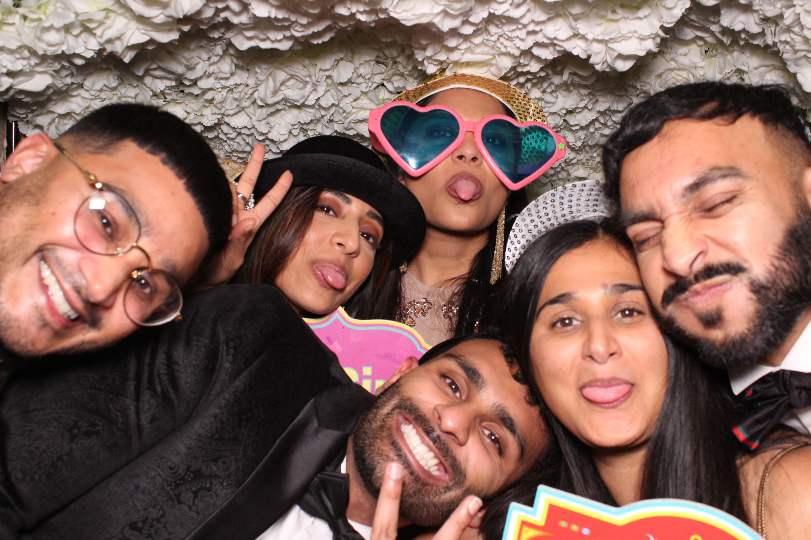 Staff posing with fun props inside a photobooth at a company celebration